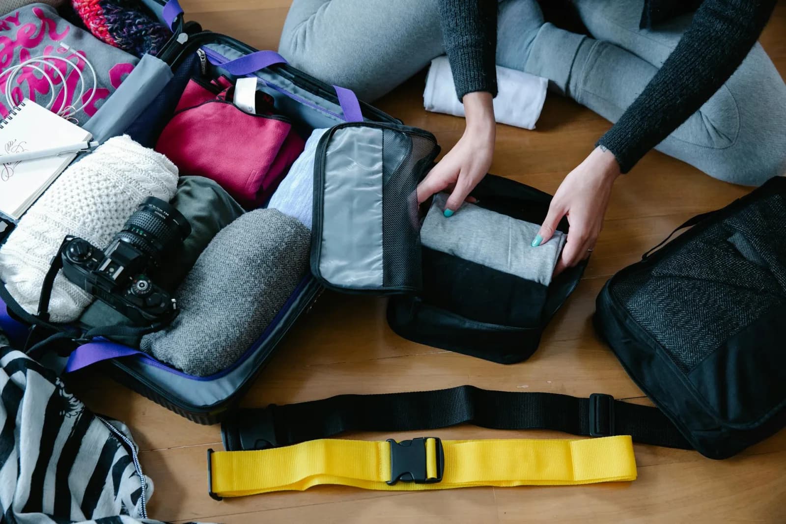An open suitcase being packed with organised packing cubes and clothing in a small room