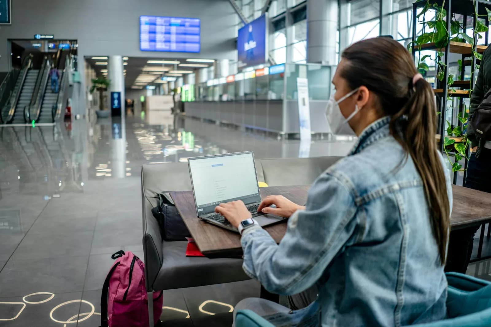 A person working on a laptop in an airport terminal, illustrating the reality of using shared public networks