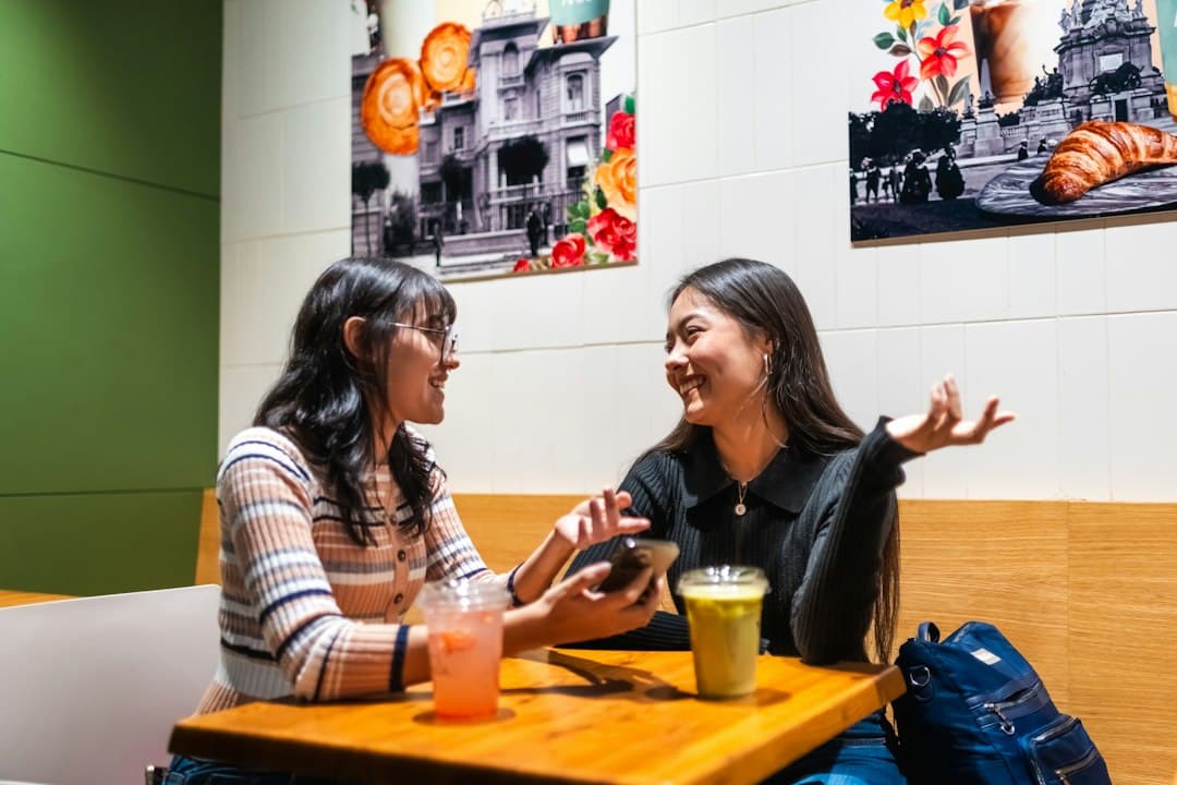 Two women talking face to face at a table with drinks.