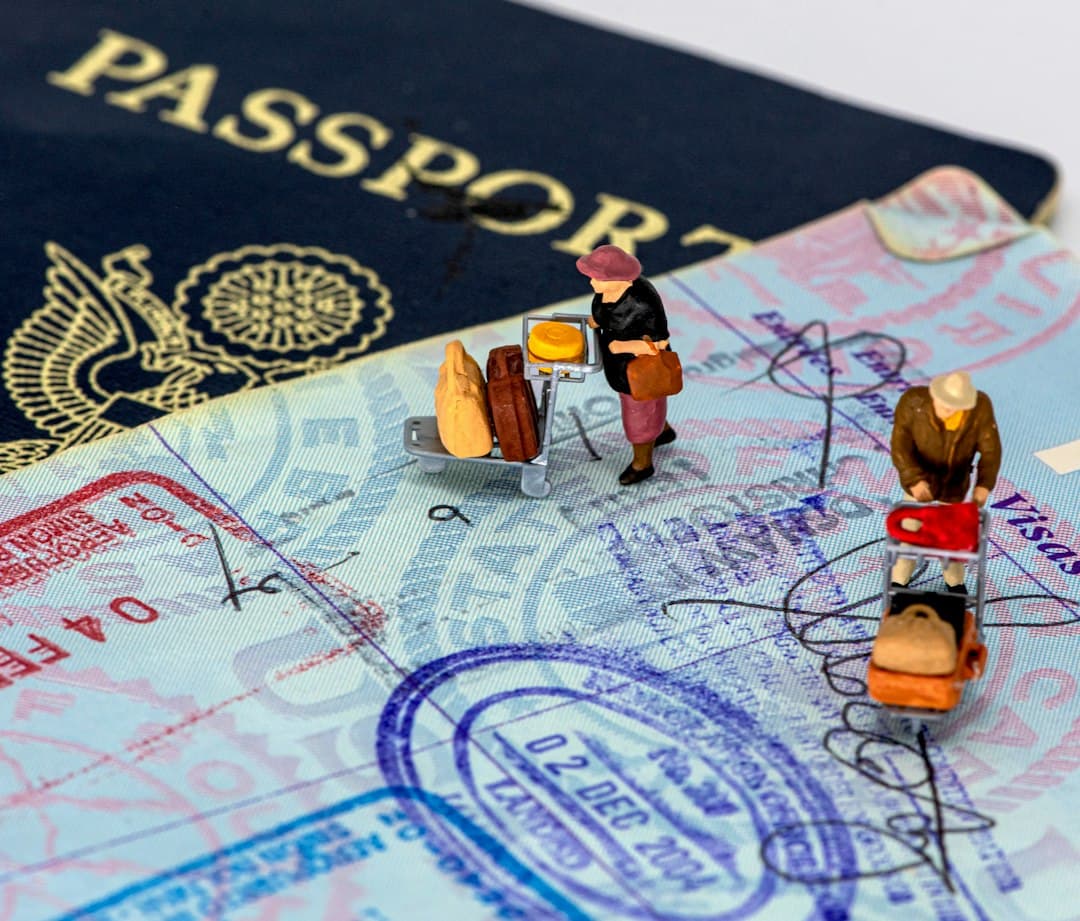 Miniature travelers with luggage on an open passport page with visa stamps.