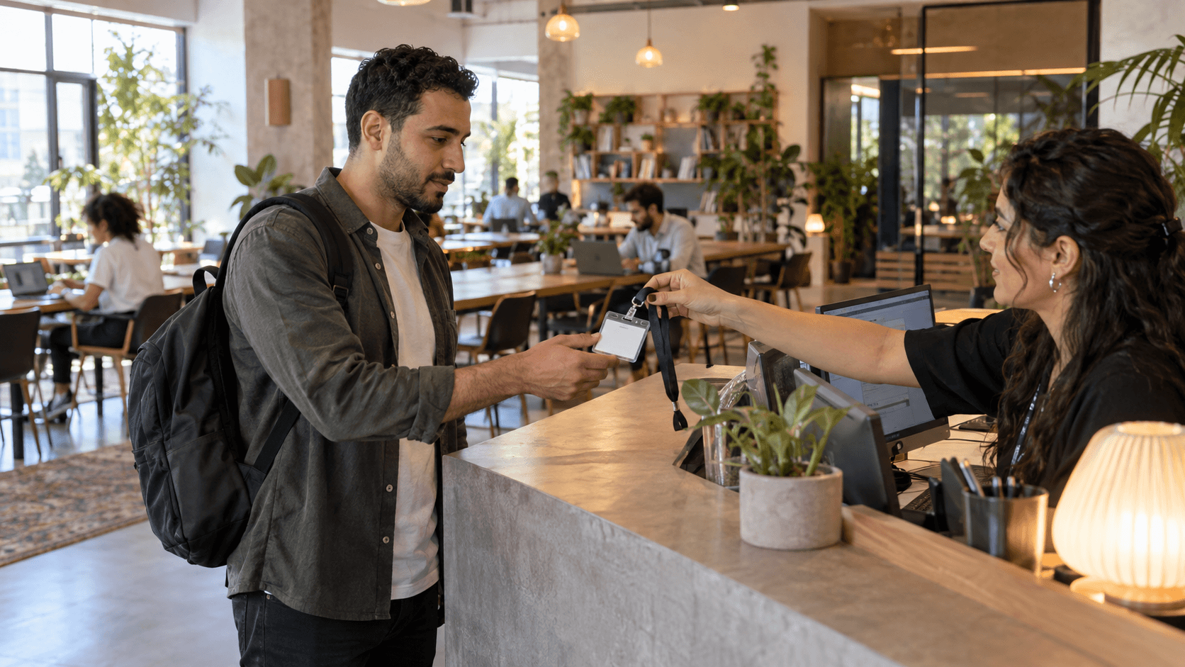 Nomade digitale che si registra alla reception di uno spazio di coworking luminoso e moderno con aree di lavoro condivise.