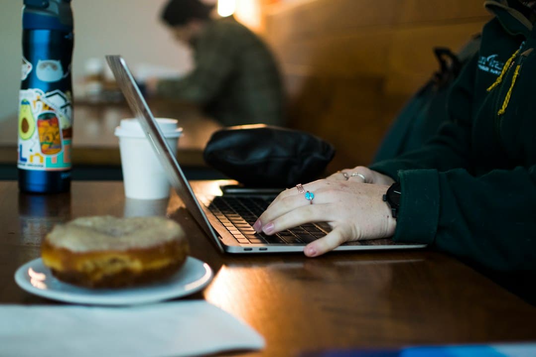 Une personne travaillant sur un ordinateur portable dans un café, illustrant la vie de nomade numérique.
