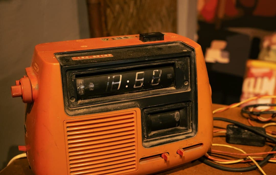 Vintage orange radio with a digital clock on a table for weather alerts.