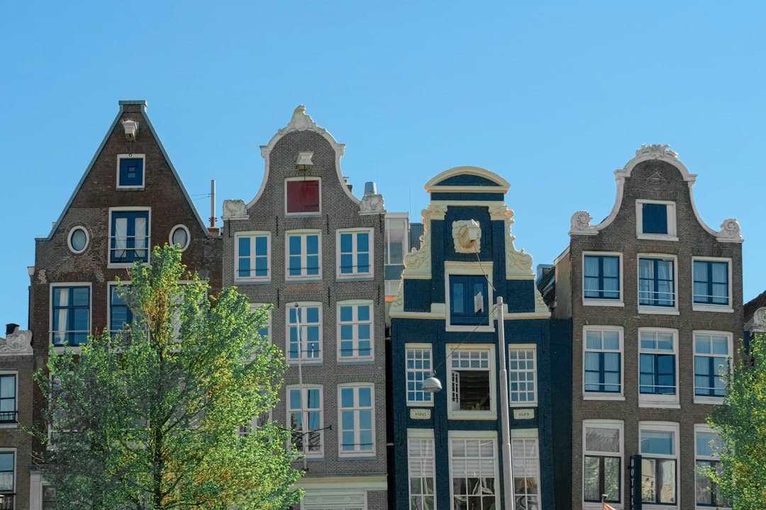 Row of traditional Dutch brick buildings with gabled roofs and large windows under a blue sky.