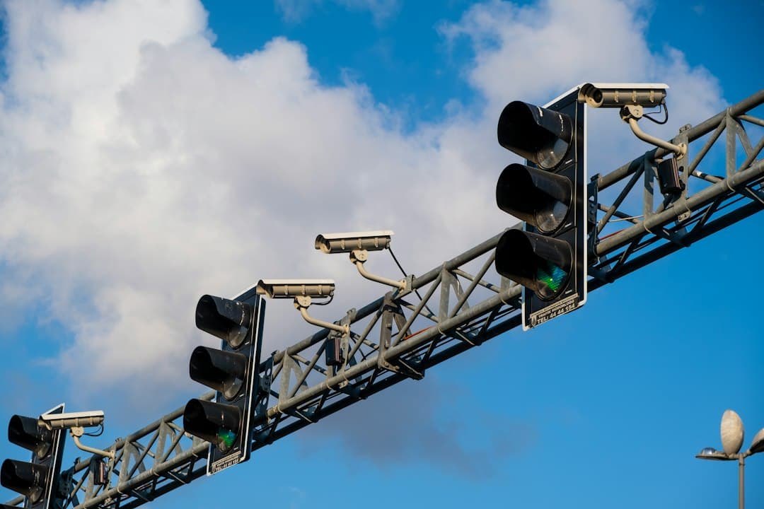 Traffic lights and surveillance cameras mounted on a metal gantry above a road.