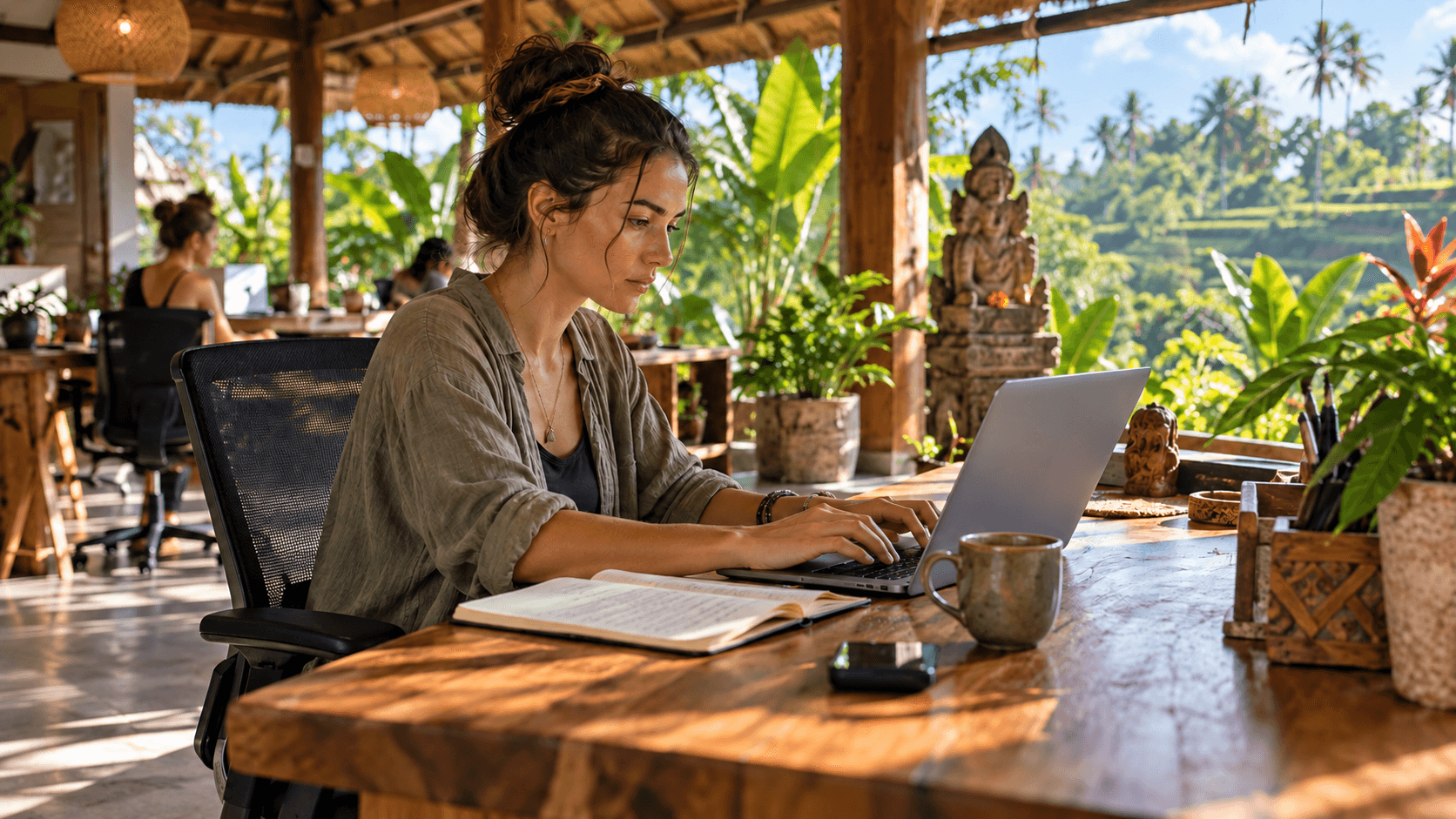 A woman working on her laptop in an outdoor tropical coworking space with palm trees in the background.