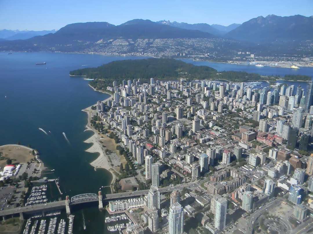 Aerial view of Vancouver's dense downtown core with residential towers, the sea and mountains in the background.
