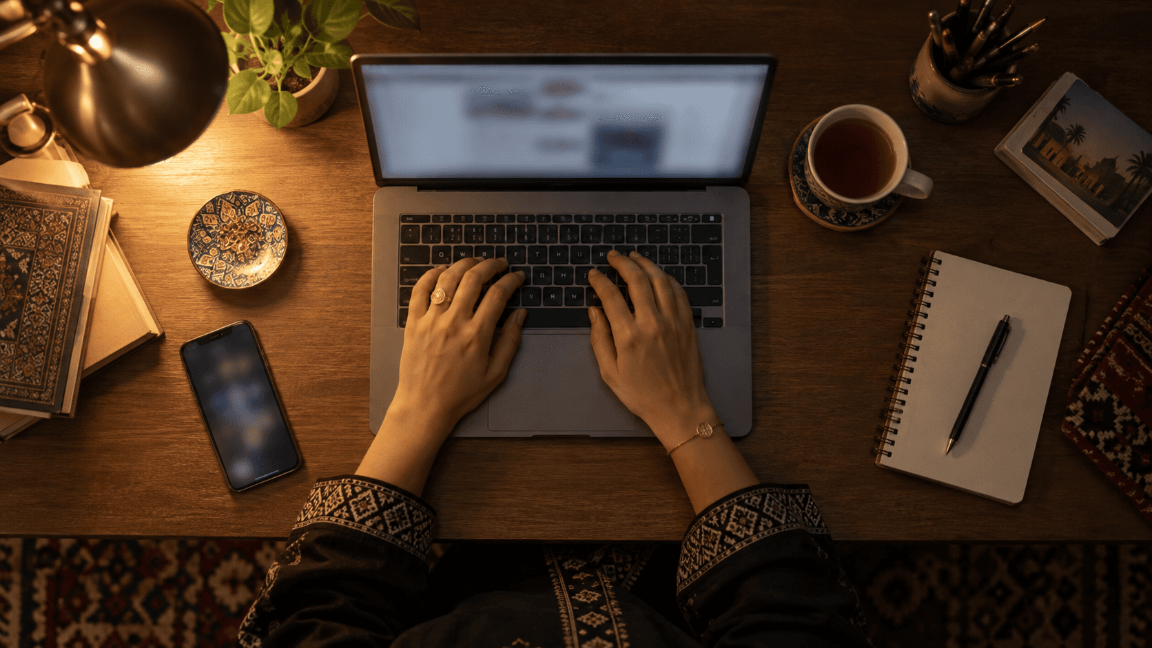 Digital nomad working on a laptop at an organized desk with coffee and a notebook in a bright space.