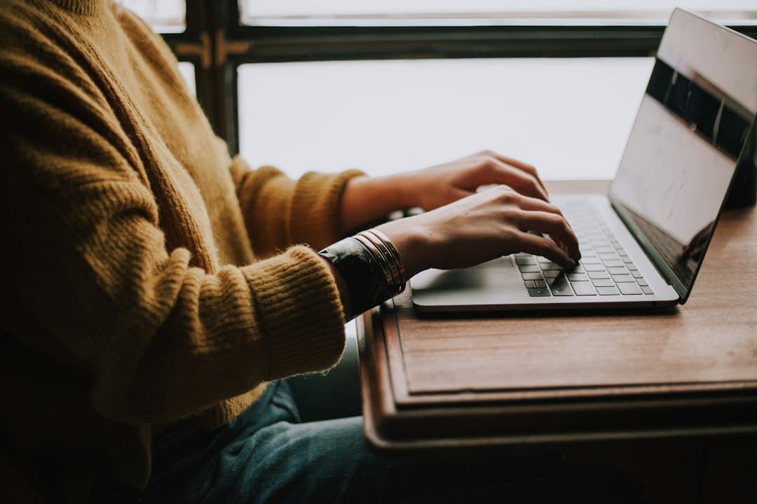 Une personne travaillant sur un ordinateur portable à un bureau près d'une fenêtre.