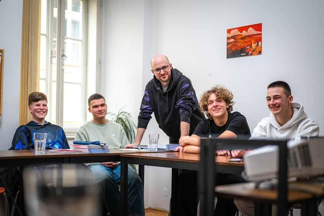 Adult instructor and four participants seated at a table in a bright room during a group learning activity.