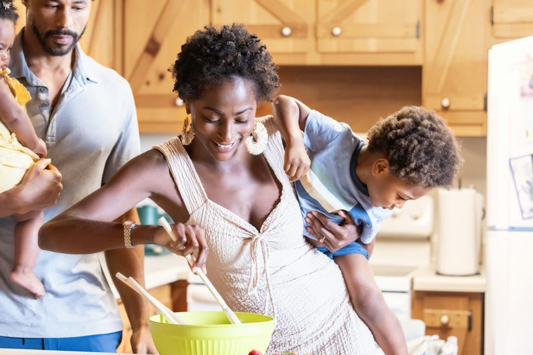 Un parent et un enfant préparant un repas ensemble dans une cuisine lumineuse et chaleureuse en famille.