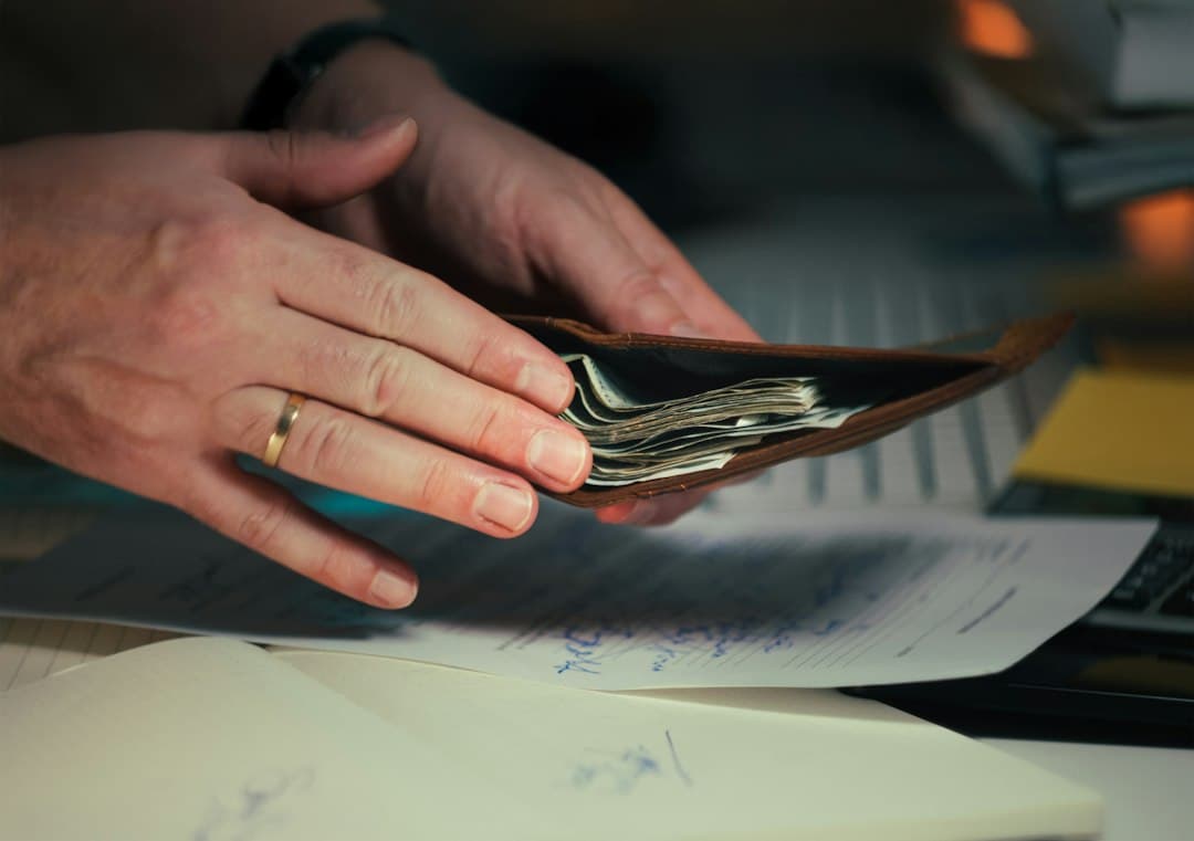 Main tenant un portefeuille ouvert avec des billets au-dessus de documents sur une table