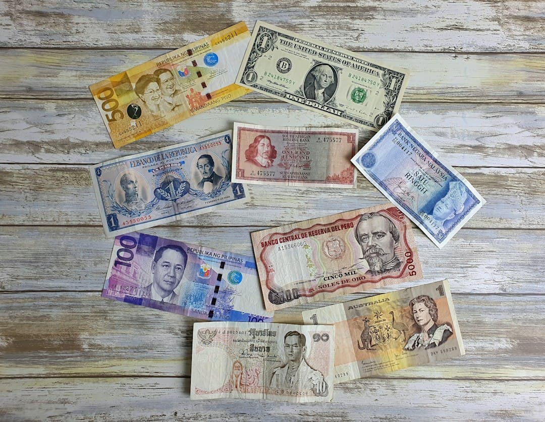 Several banknotes in various international currencies laid out on a wooden surface