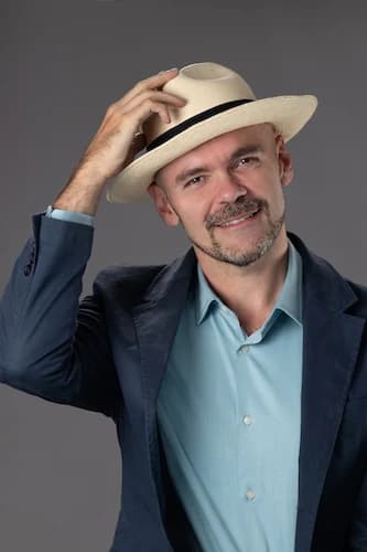 Fabrice Dubesset, la main sur le bord de son chapeau de paille, regarde l’objectif