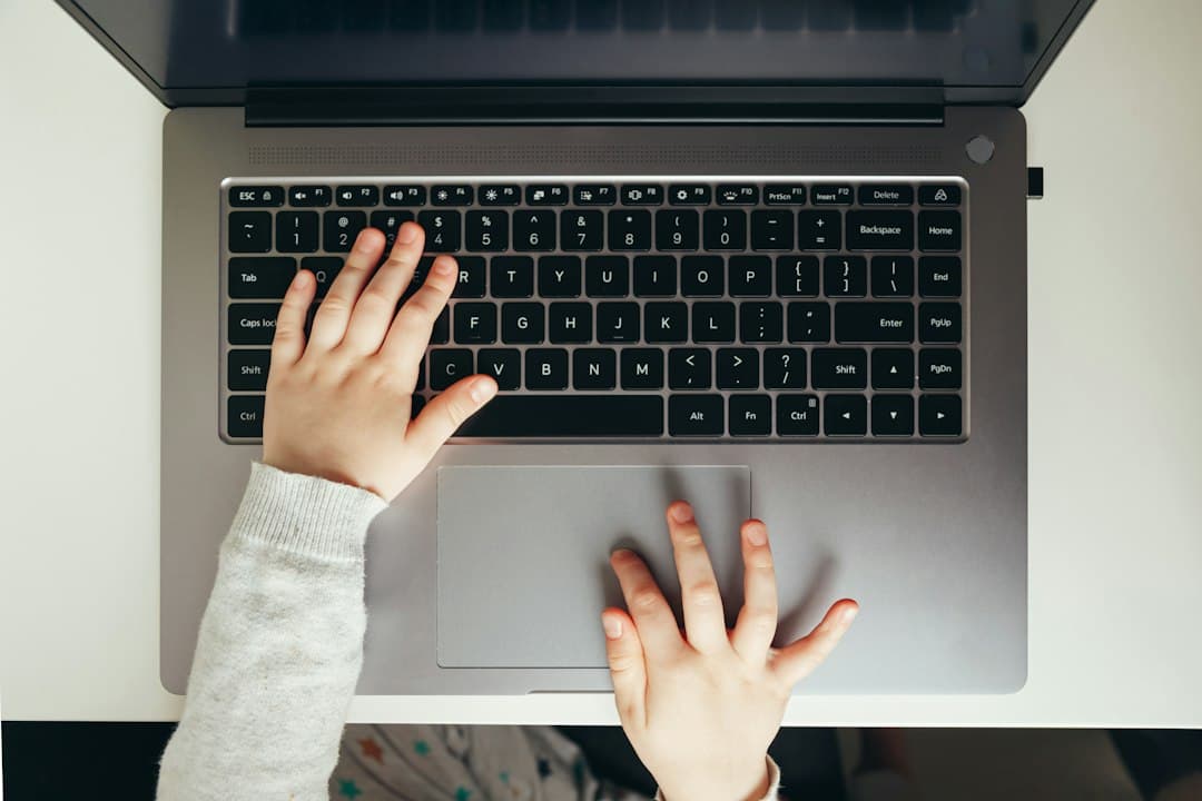 Mains d'enfant tapant sur le clavier d'un ordinateur portable lors d'une séance d'apprentissage en ligne.