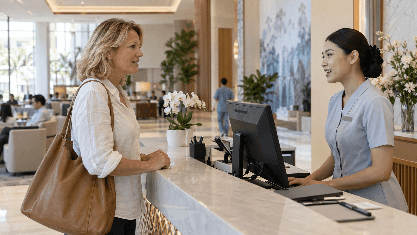 Woman at the reception desk of a modern hospital with a waiting area and staff in the background.