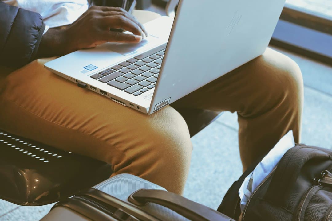 Digital nomad reviewing documents on a laptop with a travel backpack nearby.