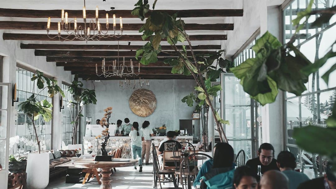 Espacio de coworking luminoso con personas trabajando en portátiles, plantas y luz natural.