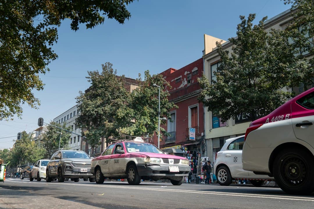 Officiële roze-witte taxi geparkeerd in een straat in Mexico-Stad met koloniale gebouwen.