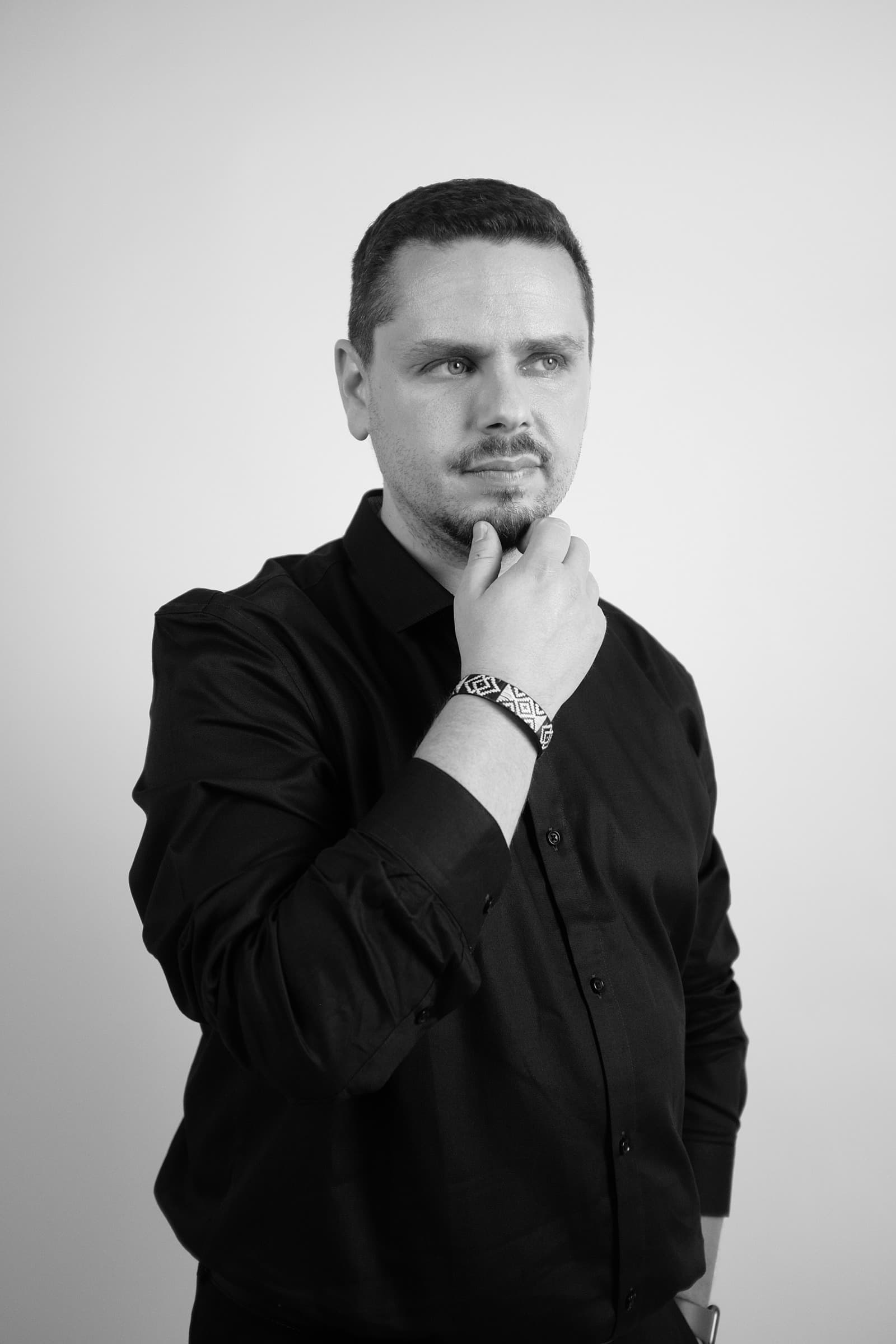 Portrait en noir et blanc de Cédric Tumminello, la main au menton, le regard tourné vers l’horizon.