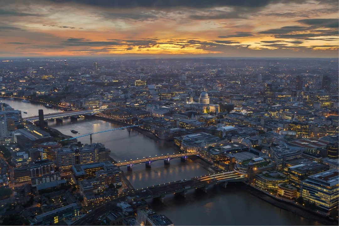London skyline at dusk with the Thames, bridges and illuminated buildings reflected in the water.