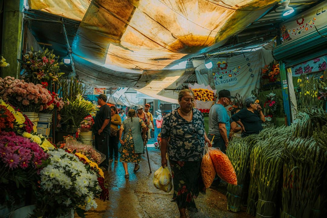 Mercado de Jamaica flower market with orange cempasúchil and colorful flowers stacked on stalls during the Día de Muertos season.