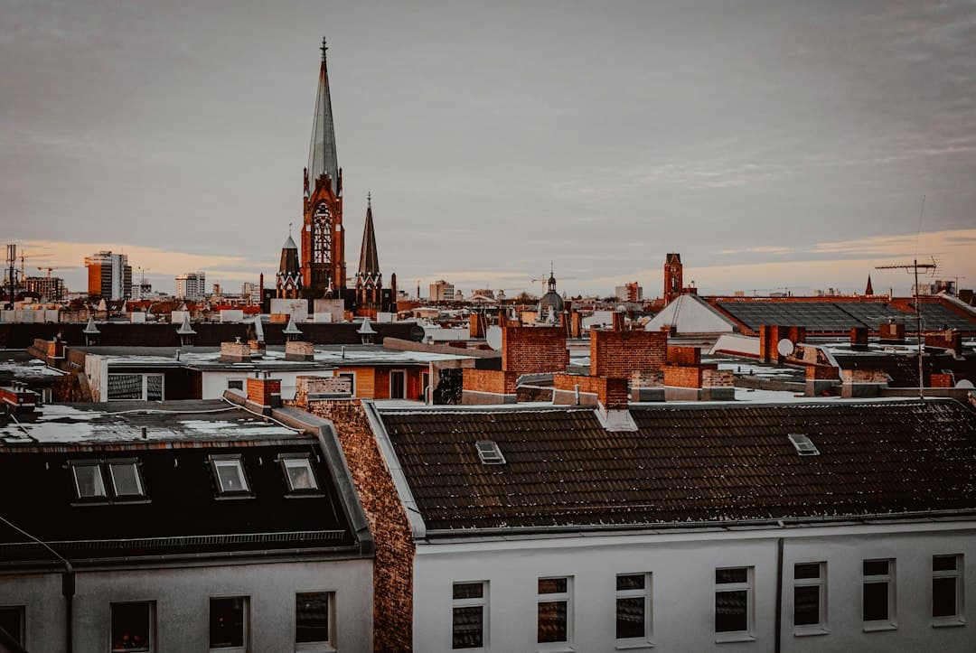 Aerial view of the rooftops of a European town with a church steeple under a cloudy sky