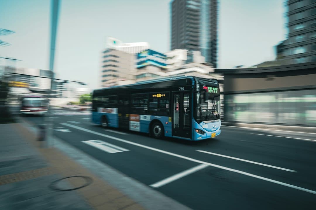 Bus urbain circulant dans une rue animée avec immeubles modernes et voies de circulation visibles.