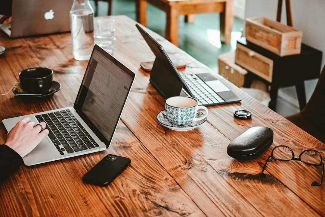 Una persona che lavora su un computer portatile a un tavolo di legno in uno spazio di coworking.