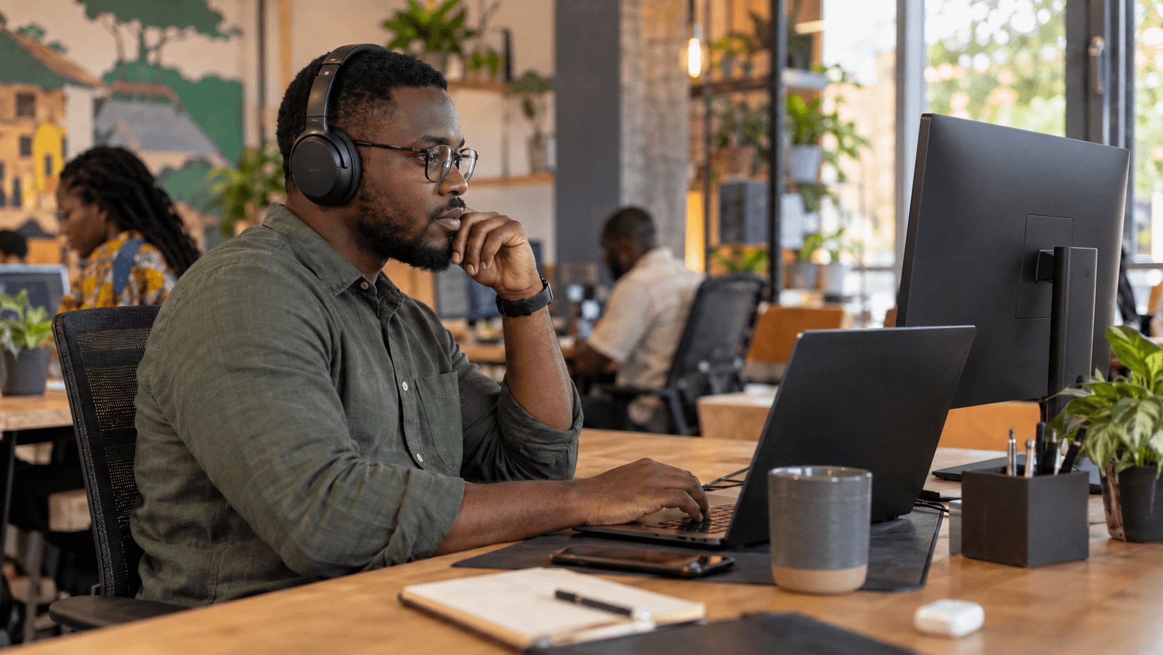 Digital nomad working at a desk in a bright coworking space with a laptop and monitor