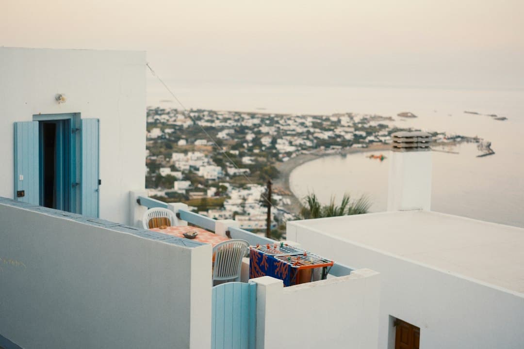 Greek apartment balcony with a sea view overlooking a small coastal town and a bay.