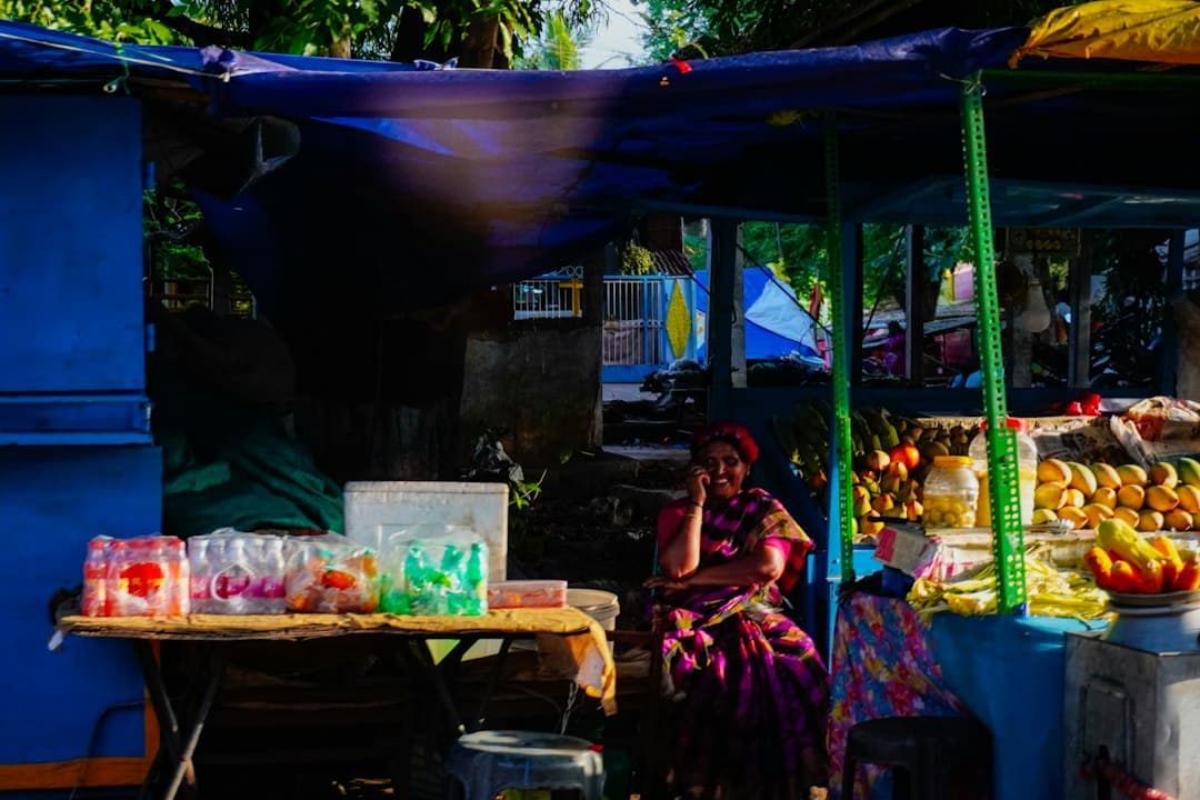 Vendor at a local market stall with fresh fruits and vegetables, Southeast Asian market atmosphere.